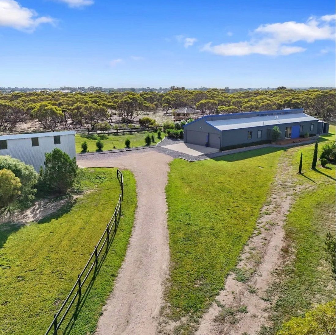 Aerial view of a large building with a surrounding green landscape and clear blue sky.
