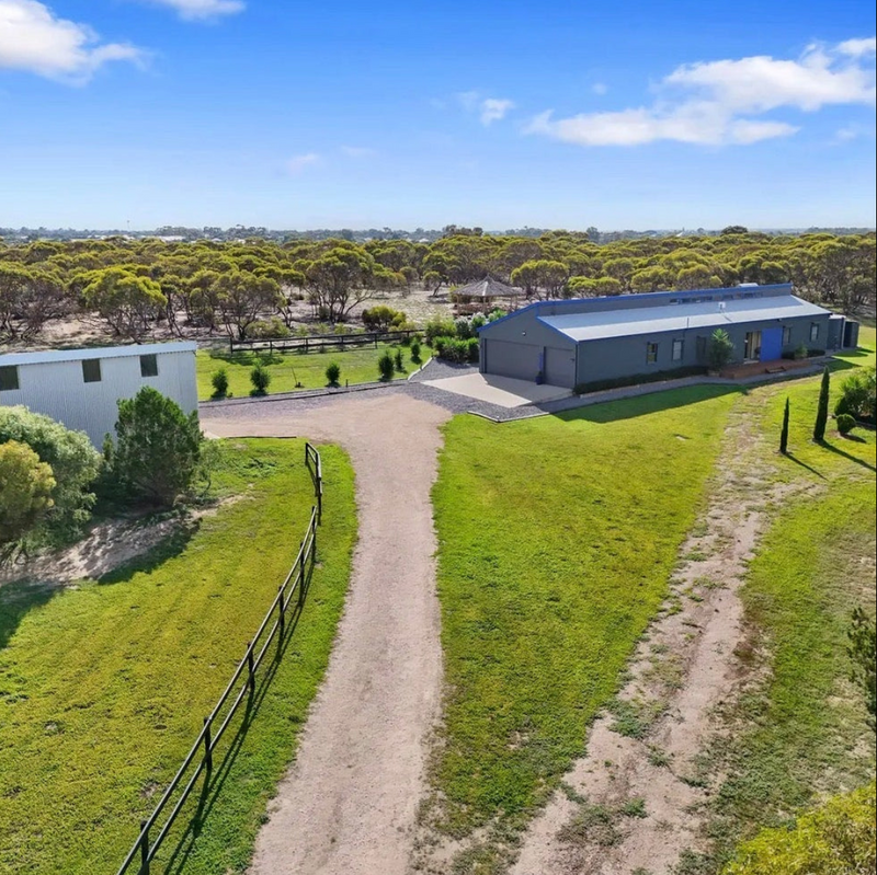 Aerial view of a large building with a surrounding green landscape and clear blue sky.